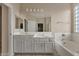 Bright bathroom featuring double sinks, a large mirror, and a separate bathtub and shower at 18611 E Raven Dr, Queen Creek, AZ 85142