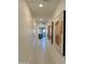 A long, brightly lit hallway with ceramic tile floors, doors, and elegant artwork adorning the walls at 20610 W Vermont Ave, Buckeye, AZ 85396