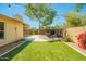 The backyard features an artificial lawn, a seating area, a stone patio, and mature trees at 2246 E Glenrosa Ave, Phoenix, AZ 85016
