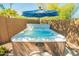 Inviting backyard hot tub featuring a built-in umbrella and wood-look siding against a brick surround at 2246 E Glenrosa Ave, Phoenix, AZ 85016