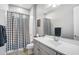 Well-lit bathroom features a black and white checkered shower curtain, a large mirror, and vanity with gray cabinets at 2617 S Jeffry St, Gilbert, AZ 85295