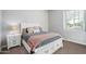 Cozy bedroom features a comfortable bed with a decorative throw and a white nightstand with lamp near a bright window at 2617 S Jeffry St, Gilbert, AZ 85295