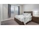 Inviting bedroom with a wooden bed frame, side table, and a bright window with gray curtains for a serene atmosphere at 2617 S Jeffry St, Gilbert, AZ 85295