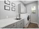 Functional laundry room with a sink, white washer and dryer, grey cabinets, and decorative framed pictures at 2617 S Jeffry St, Gilbert, AZ 85295
