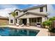Backyard view featuring a pristine pool, covered patio, and lush greenery at 30246 N 123Rd Ln, Peoria, AZ 85383