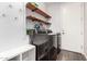 Well-lit laundry room featuring front loading washer/dryer, floating wood shelves, and white storage bench at 30246 N 123Rd Ln, Peoria, AZ 85383