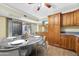 Charming kitchen featuring wood cabinets, an island, open layout and a view of an outdoor patio through sliding glass doors at 3220 W Laurie Ln, Phoenix, AZ 85051