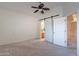 Spacious bedroom featuring a ceiling fan, carpet, and sliding barn door leading to the bathroom at 3310 E Fremont Rd, Phoenix, AZ 85042
