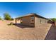 Wide view of the backyard featuring gravel, patio, and small patch of grass with stone firepit at 41290 W Ganley Way, Maricopa, AZ 85138