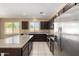 Modern kitchen with stainless steel appliances, granite countertops, and dark wood cabinets at 41290 W Ganley Way, Maricopa, AZ 85138
