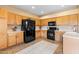 Well-lit kitchen featuring black appliances, tile flooring, and wood cabinets providing a functional cooking space at 42410 N 46Th Ln, Phoenix, AZ 85086