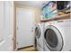 Well-lit laundry room with washer, dryer, storage shelves, and tile flooring at 42410 N 46Th Ln, Phoenix, AZ 85086