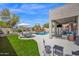 Inviting backyard pool and patio area features lounge chairs, umbrella, seating, lush lawn and covered patio at 7242 E Tyndall St, Mesa, AZ 85207
