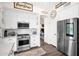 Bright kitchen featuring white cabinets, stainless steel appliances, and wood-look floors, perfect for modern farmhouse charm at 7242 E Tyndall St, Mesa, AZ 85207