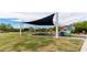 Community playground with shade cover, climbing structures, and lush green grass at 7242 E Tyndall St, Mesa, AZ 85207
