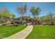 Lush, green lawns lead to a stunning home with desert landscaping and mature trees on a clear, sunny day at 7445 E Eagle Crest Dr # 1122, Mesa, AZ 85207