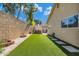 A backyard with artificial turf, stepping stones, and a desert landscape accented by a brick feature and privacy fencing at 8972 E Arizona Park Pl, Scottsdale, AZ 85260