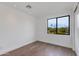 Minimalist bedroom with hardwood floors, white walls, and a large window at 100 W Northern Ave # 15, Phoenix, AZ 85021