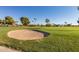 Golf course scene featuring a sand trap with green grass, palm trees, and blue sky at 10461 W Hutton Dr, Sun City, AZ 85351