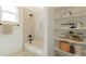 Bright bathroom featuring a shower-tub combo with white tile and a stylish built-in shelving unit filled with accessories at 10829 W Woodruff Rd, Casa Grande, AZ 85194