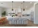 Elegant kitchen featuring white cabinetry, pendant lighting, a large island with seating, and stainless steel appliances at 10829 W Woodruff Rd, Casa Grande, AZ 85194