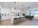 Bright open-concept kitchen featuring an island with seating and stylish lighting adjacent to a dining area at 10947 W Woodruff Rd, Casa Grande, AZ 85194