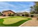Backyard featuring a well-maintained putting green, desert landscaping, and mature shrubbery at 11277 W Buchanan St, Avondale, AZ 85323