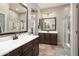 Modern bathroom features dual sinks, dark wood cabinets, and a glass-enclosed shower at 12047 W Red Hawk Dr, Peoria, AZ 85383