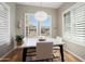 Dining area with white table, modern lighting, and bright windows with plantation shutters at 12047 W Red Hawk Dr, Peoria, AZ 85383