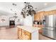 Open kitchen features stainless steel appliances, light wood cabinets, and a central island with hanging pot rack at 1344 N Constellation Way, Gilbert, AZ 85234