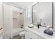 Modern bathroom features a shower-tub combo, neutral tile, and white vanity with black hardware at 13947 E Barwick Dr, Scottsdale, AZ 85262