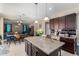 Kitchen island with granite countertop, seating, and view of the open-concept living space at 15856 N 76Th Ave, Peoria, AZ 85382