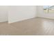 Bright bedroom with wood-look tile flooring, white walls, and a window providing natural light at 16076 W Prickly Pear Trl, Surprise, AZ 85387