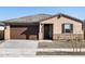 Single-story home featuring a brown garage door, rock facade, and desert landscaping at 16076 W Prickly Pear Trl, Surprise, AZ 85387