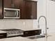 Modern kitchen featuring stainless steel appliances, dark wood cabinets, and subway tile backsplash at 16076 W Prickly Pear Trl, Surprise, AZ 85387