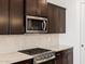 Close up of modern kitchen with stainless steel appliances, dark wood cabinets and subway tile backsplash at 16076 W Prickly Pear Trl, Surprise, AZ 85387