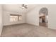 Sunlit living room featuring neutral carpet, access to a kitchen, and a ceiling fan at 1716 N Temple St, Mesa, AZ 85203