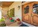 Elegant front door featuring custom wood design and a decorative lantern, enhanced by lush plants and flowers at 1934 E Hale St, Mesa, AZ 85203