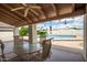 Covered patio with a dining set, offering views of a sparkling pool and lush landscaping for outdoor relaxation at 1934 E Hale St, Mesa, AZ 85203