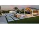 Backyard oasis with a pool, fire pit, outdoor seating and lush desert landscaping at 19901 E Country Meadows Dr, Queen Creek, AZ 85142