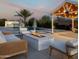 Backyard oasis with a pool, fire pit, outdoor seating and lush desert landscaping at dusk at 19901 E Country Meadows Dr, Queen Creek, AZ 85142