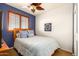 Charming bedroom with natural light from the window, a ceiling fan, and a cozy bed with blue accents at 21557 N Anne Ln, Maricopa, AZ 85138