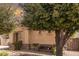 Charming home exterior featuring mature trees, desert landscaping, and a cozy bench for relaxing outdoors at 21557 N Anne Ln, Maricopa, AZ 85138