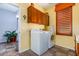 Laundry room with yellow walls, cabinets, tile floor, a window with shutter, and washer and dryer at 21557 N Anne Ln, Maricopa, AZ 85138