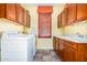Laundry room with yellow walls, cabinets, tile floor, a window with shutter, and washer and dryer at 21557 N Anne Ln, Maricopa, AZ 85138