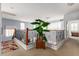 Spacious loft area with decorative wrought iron railing, large potted tree, and neutral carpet at 21557 N Anne Ln, Maricopa, AZ 85138