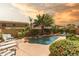 A serene backyard pool featuring a rock waterfall, palm trees, and a private patio area at 21557 N Anne Ln, Maricopa, AZ 85138