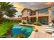 A stunning backyard oasis with a sparkling pool, lush landscaping, and a charming two-story home at 21557 N Anne Ln, Maricopa, AZ 85138