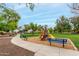 Community playground with swingset and bench seating surrounded by lush green grass and mature trees at 2319 E San Tan Dr, Gilbert, AZ 85296