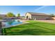An appealing backyard with a well-maintained pool, artificial grass and sitting area for relaxing and entertaining at 30370 N Opal Dr, San Tan Valley, AZ 85143